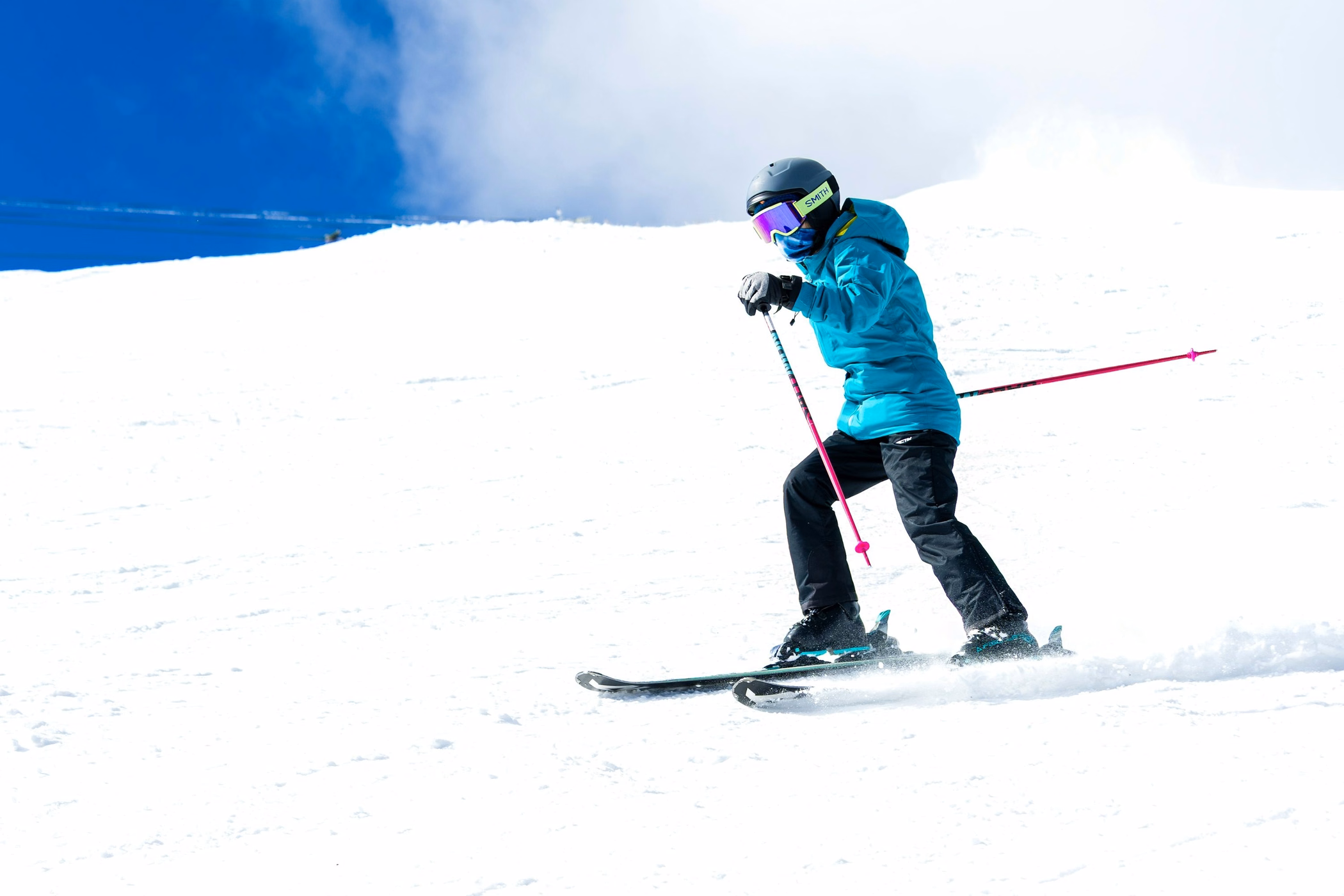 A skier turning down a bright, snow-covered slope